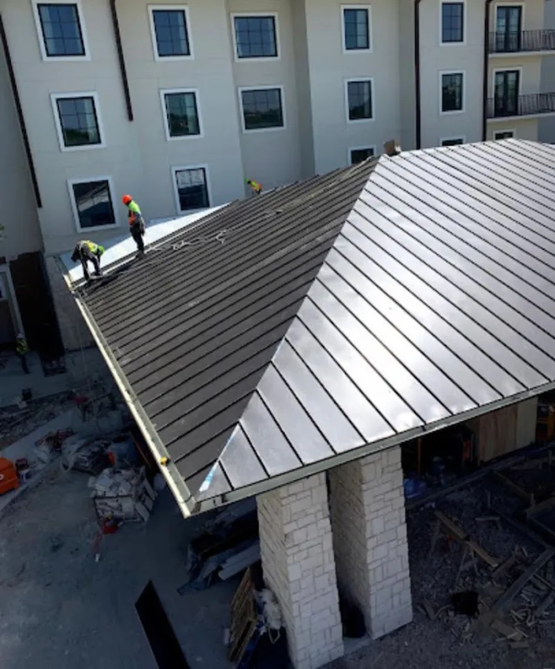 Crew installing standing seam metal roof panels on a commercial project in Milton